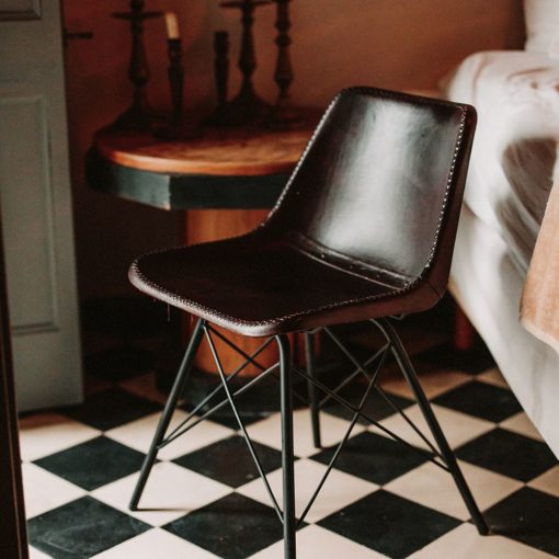 SILLA DE PIEL CAMELOT, de estilo industrial con estructura tubular de acero con acabado en negro y asiento de PP tapizado en piel color marrón oscuro. sesión